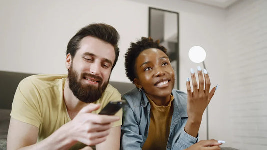 Couple smiling while using smartphone together in cozy living room setting