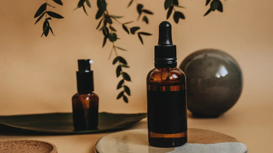 Amber glass dropper bottle with black label, set with greenery and stone decor for adult wellness products.