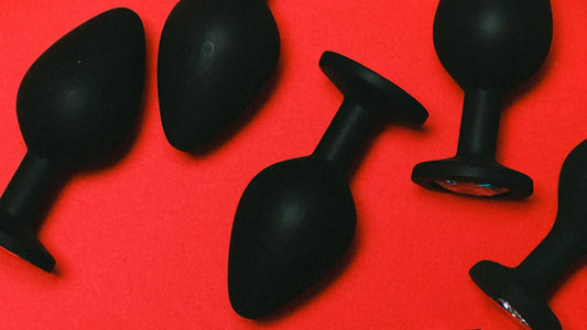 Black silicone anal plugs on red background, adult toys for intimate pleasure