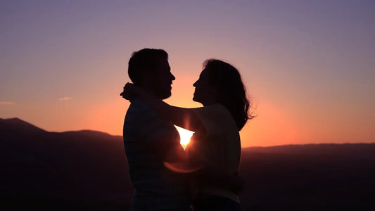 Romantic couple silhouette at sunset, embracing with sun between them