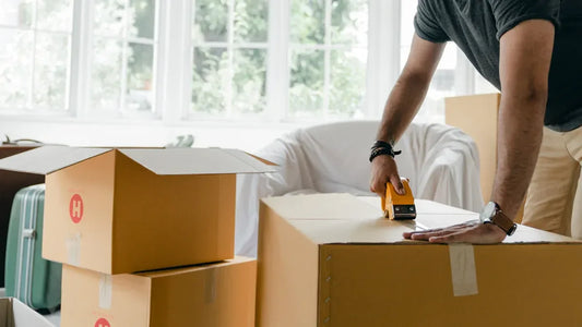 Man sealing cardboard boxes with tape for discreet adult product delivery