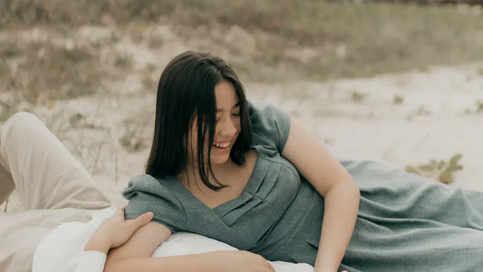 Woman in gray dress laughing on sandy beach with partner